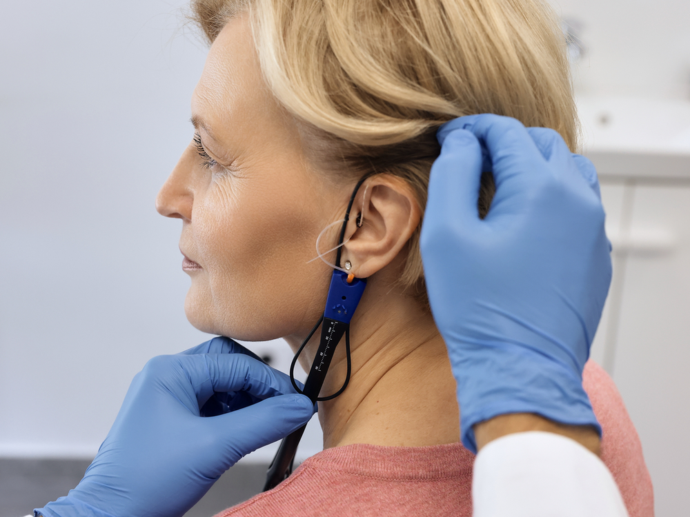 Doctor of Audiology performing real ear measurement on a hearing aid patient at Precision Hearing in San Antonio, TX